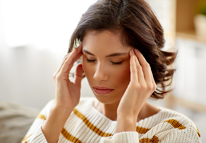 Frau mit Kopfschmerzen als Symptom einer Lebensmittelallergie